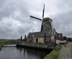 An image of a windmill with a small restaurant and canal.