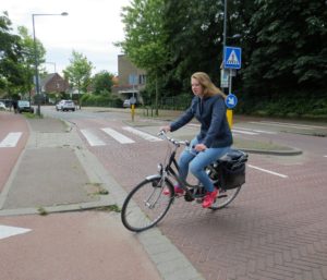 A woman cycling through a cycle crossing on a street.