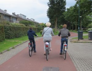 A female senior bikes between two teenage boys.