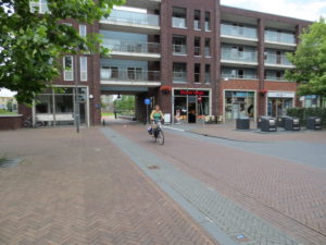 A woman bikes along a bike path which travels under a building.